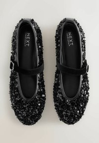 Bailarinas negras con lentejuelas, con punta brillante negra y una correa de terciopelo. Presentan un intrincado detalle de lentejuelas en la parte superior.