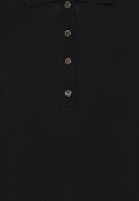 Polo nero in maglia testurizzata, con colletto e sei bottoni in metallo argentato disposti lungo la parte anteriore.