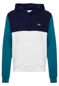 Mikina s kapucí, která má námornickou horní část, bílý střední panel a tyrkysové rukávy. Obsahuje přední kapsu a logo Lacoste.