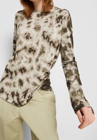 T-shirt z długim rękawem w tie-dye w odcieniach beżu i oliwki, z okrągłym dekoltem i zaokrąglonym dołem, wykonany z miękkiego, lekkiego materiału.