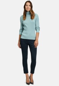 Light blue ribbed turtleneck sweater with long sleeves, combined with dark navy slim-fit pants and black pointed-toe heels.