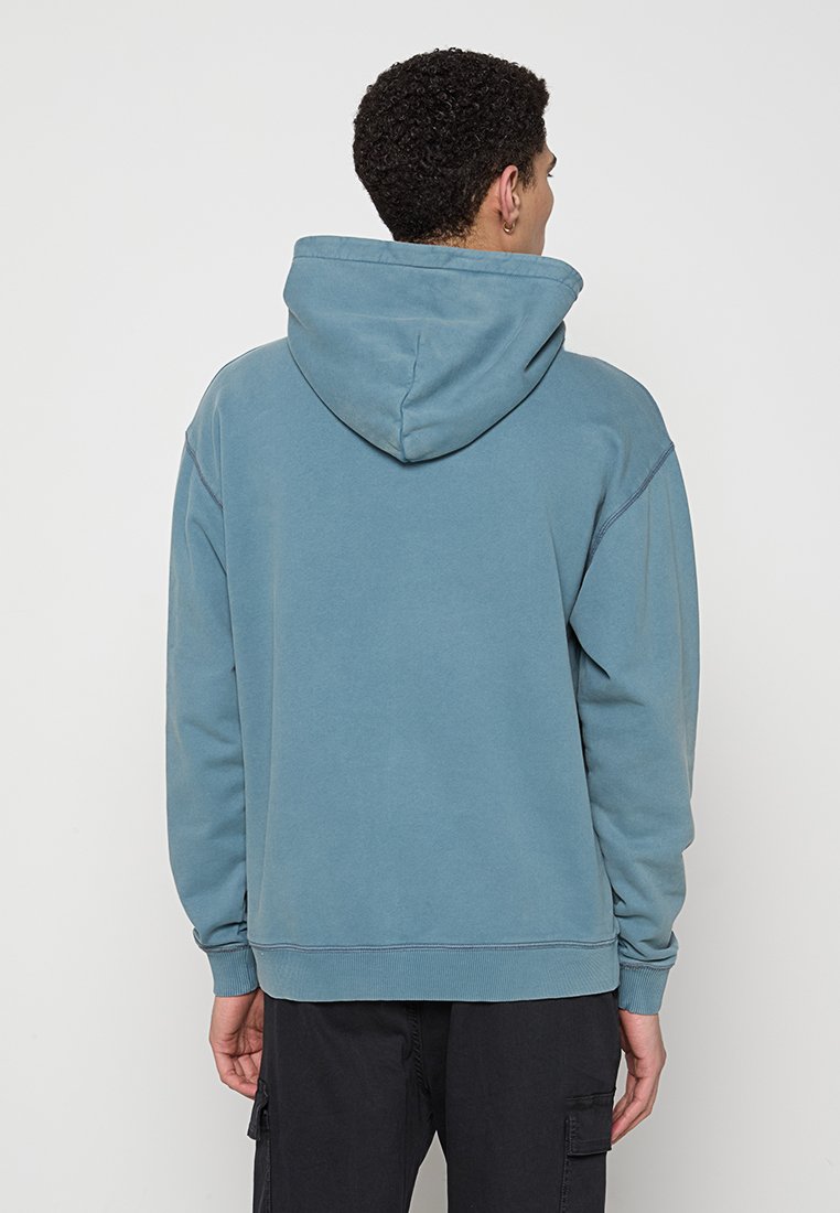 Ausgewaschene blaue Kapuzenjacke mit Kordelzugkapuze, oversize Schnitt, gerippte Bündchen und Saum, aus weichem Stoff, mit einem schlichten Rückendesign.