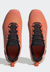 Korale i czarne buty sportowe z teksturowaną siateczkową cholewką, wzmocnionym noskiem, kontrastowymi sznurowadłami i pętelką na pięcie. Posiadają gumową podeszwę.