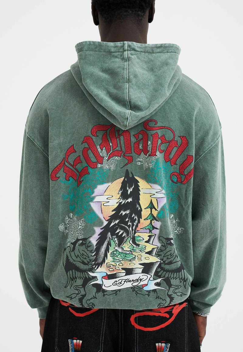 Groene hoodie met een afbeelding van een zwarte wolf tegen een kleurrijk landschap. Beschikt over een trekkoordkap en een losse pasvorm. Inclusief Ed Hardy-merktekens.
