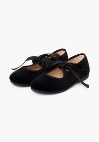 Zapatos de ballet de terciopelo negro con puntas redondeadas, forro interior de cuero y cintas negras que se cruzan sobre el empeine. Suela plana y flexible.