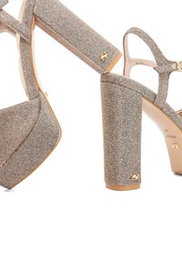 Platform sandalen met hoge hakken van een gestructureerde, metallic stof in champagnekleur. Heeft een chunky hak en gouden hardware-accenten.