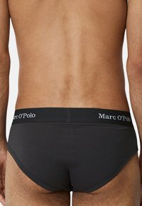 Schwarze Baumwollunterhose mit glatter Textur, ausgestattet mit einem gerippten Bund, der mit "Marc O'Polo" beschriftet ist. Das Design ist minimalistisch und enganliegend.