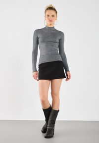 Gray ribbed long-sleeve top with high neck, paired with a black A-line mini skirt and knee-high black leather boots with buckle accents.