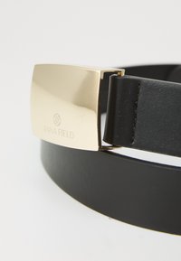 Svart lærbelte med et gullfarget rektangulært spenne med preget merkevarelogo, glatt tekstur og elegant design.