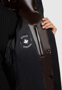 Black puffer jacket with glossy, dark brown inside lining. Features a logo in white, snap button closure, and side pockets.