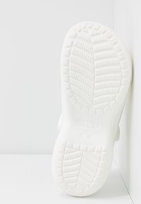 Vit Crocs-sko sula med texturerat mönster, med upphöjda klackar och slät kant. Logotyp och storlek tryckt på sulan.
