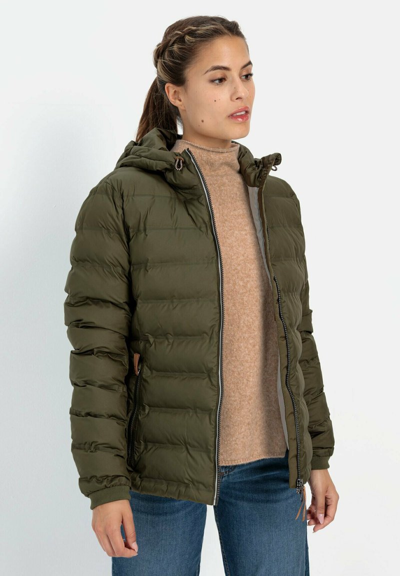 Padded olive green jacket with a hood, featuring a front zipper, side pockets, and ribbed cuffs, worn over a tan sweater and blue jeans.