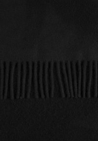 Svart fleecefilt med en texturerad franskant på ena sidan, mjukt material och en jämn, slät yta.