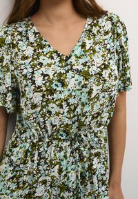 Blumenkleid mit V-Ausschnitt, kurzen Puffärmeln, im Muster aus Blau, Grün und Schwarz. Mit gebundenem Taillendetail, aus weichem Stoff.