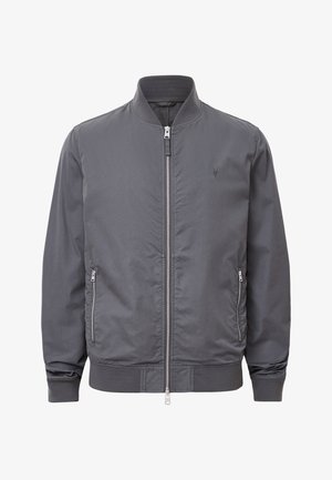 Harmaa pommikätkä, jossa on röyhelökaulus, vetoketjulla oleva etuosa ja kaksi sivutaskua. Erittäin sileä pinta, jossa on sävyttävä logoyksityiskohta rinnassa.