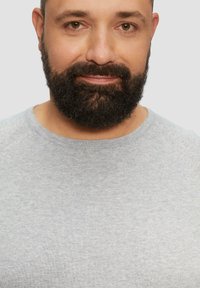 Graues Kurzarmhemd mit rundem Halsausschnitt. Der Stoff wirkt weich und leicht strukturiert, getragen von einem Mann mit vollem Bart.