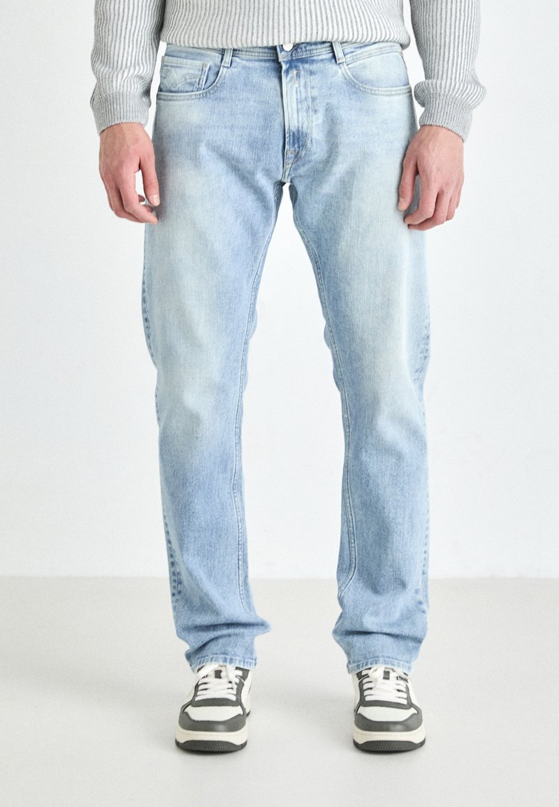 Lys blå denimjeans med avslappet passform, har en femlommersdesign og subtle falming. Kombinert med svarte og hvite sneakers.