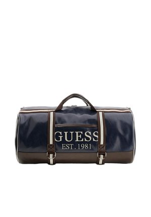 Borsa duffle Guess blu navy e marrone con rifiniture bianche, tasca frontale con zip, scritta del logo "GUESS EST. 1981" e doppi manici con tracolla a righe.