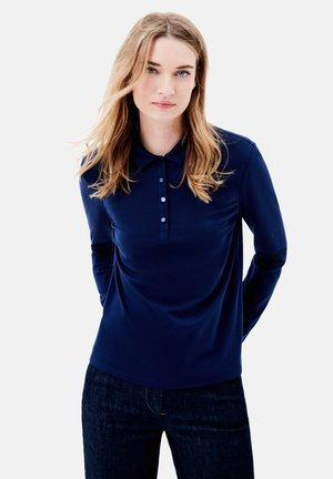 Navy lange mouw polo shirt met een kraag, drie-knopsluiting en een gladde textuur; gecombineerd met een donkere denim jeans.