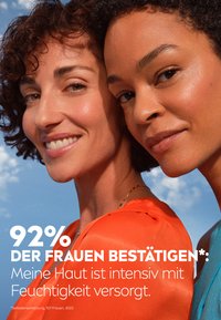 Two women smiling, one with curly hair in a bright orange top, the other in a turquoise top. Smooth skin, blue sky background, and text overlay.