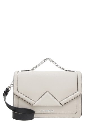 Beżowa prostokątna torebka z czarnym odpinanym paskiem, srebrnym łańcuszkowym uchwytem oraz małym srebrnym logo "KARL LAGERFELD" na przedniej klapie.