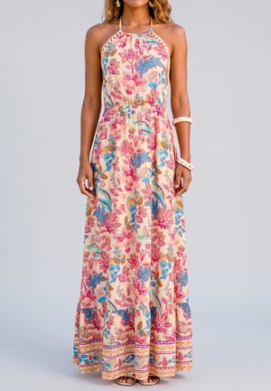 Frau trägt ärmelloses Maxikleid mit Neckholder und bunten Blumenmustern in Pink, Blau und Orange auf hellem Hintergrund.