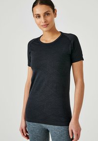 Camiseta atlética negra de manga corta con patrones geométricos texturizados; presenta un escote redondo y mangas raglán. Suitable para ropa activa.