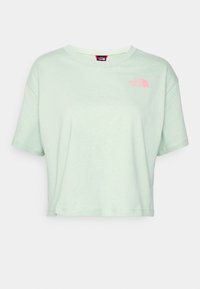 Kratší tričko s krátkým rukávem v světlé mátové zelené barvě, vyrobené z měkké bavlny, s malým růžovým logem na levé straně hrudi. Kulatý výstřih.