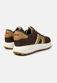 Scarpe sportive marroni con accenti beige, logo bianco, tessuto testurizzato e suola spessa bianca con suola in gomma naturale. Caratterizzate da lacci e una linguetta.
