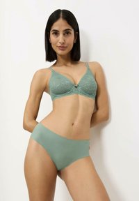 Reggiseno in pizzo verde menta con scollatura a V e spalline regolabili; abbinato a slip verde menta senza cuciture. Tessuto liscio, luminosità sottile.
