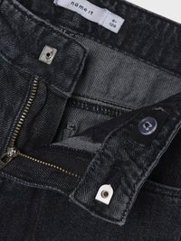 Juodos džinsinės kelnės su užtrauktuko ir sagos užsegimu, matomu etiketė, tekstūruotu audiniu ir metaliniais akcentais.
