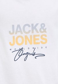 Weißer Stoff mit „JACK & JONES“ in einem Farbverlauf von Grau zu Gelb, „WORLDWIDE“ in kleinen schwarzen Buchstaben und einer schwarzen kursiven Unterschrift darunter.
