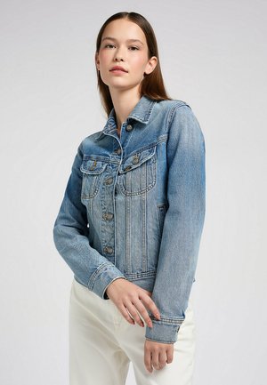 Jasnoniebieska kurtka dżinsowa z zapięciem na guziki, kieszeniami na piersi i spiczastym kołnierzem; charakteryzuje się dopasowanym krojem i widocznymi detalami przeszyć.