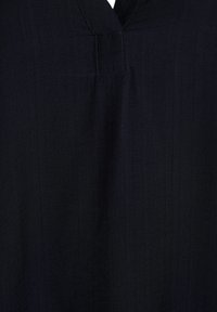 Schwarzes Oberteil aus Stoff mit V-Ausschnitt und dezenter Textur, das ein sauberes Design und minimale Nähte am Ausschnitt aufweist.