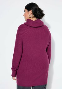 Fioletowy sweter robiony na drutach z dużym kołnierzem typu cowl, długimi rękawami i prążkowaną teksturą. Widok z tyłu ukazuje luźny krój i średniej długości design.