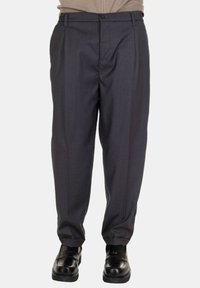 Pantaloni grigi su misura con fronte piatto, pieghe e design a gamba dritta. Il tessuto ha una consistenza liscia; la vita presenta una chiusura con bottone.