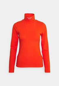 Röd långärmad polotröja i stretchigt bomullsmaterial. Har en figurnära silhuett och Calvin Klein Jeans-logotyp på kragen.