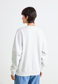 Lichtgrijze sweatshirt met een ronde halslijn, lange mouwen en een ontspannen pasvorm. Gemaakt van zachte stof met geribbelde boorden en tailleband.