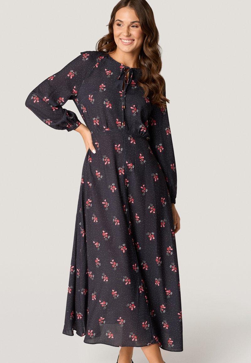 Floral maxi-jurk in donkerblauw, met kleine rode en witte bloemenpatronen, lange poffende mouwen, een ronde halslijn en een gecinchte taille.