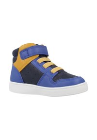 Zapatilla alta con paneles en azul, marino y amarillo, cordones amarillos, tira de velcro azul y suela blanca, aislada sobre fondo blanco.