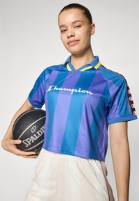 Rövidre vágott kék és lila csíkos mez sárga részletekkel és "Champion" logóval, amelyhez egy fekete Spalding kosárlabda tartozik.