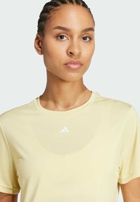 Gelbes Sport-T-Shirt mit Rundhalsausschnitt, kurzen Ärmeln und glatter Textur. Mit einem kleinen weißen Adidas-Logo auf der Brust.