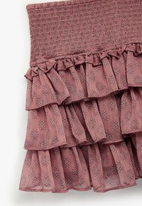 Jupe à volants en mauve avec un haut smocké. Présente un motif floral et un tissu texturé léger.