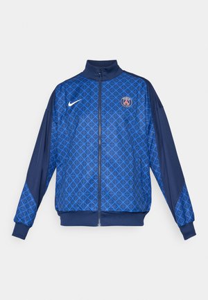 Giacca blu con zip, decorata con un motivo geometrico, caratterizzata da un colletto alto e polsini elastici. Logo Nike sul davanti, insieme a un distintivo a tema Parigi.