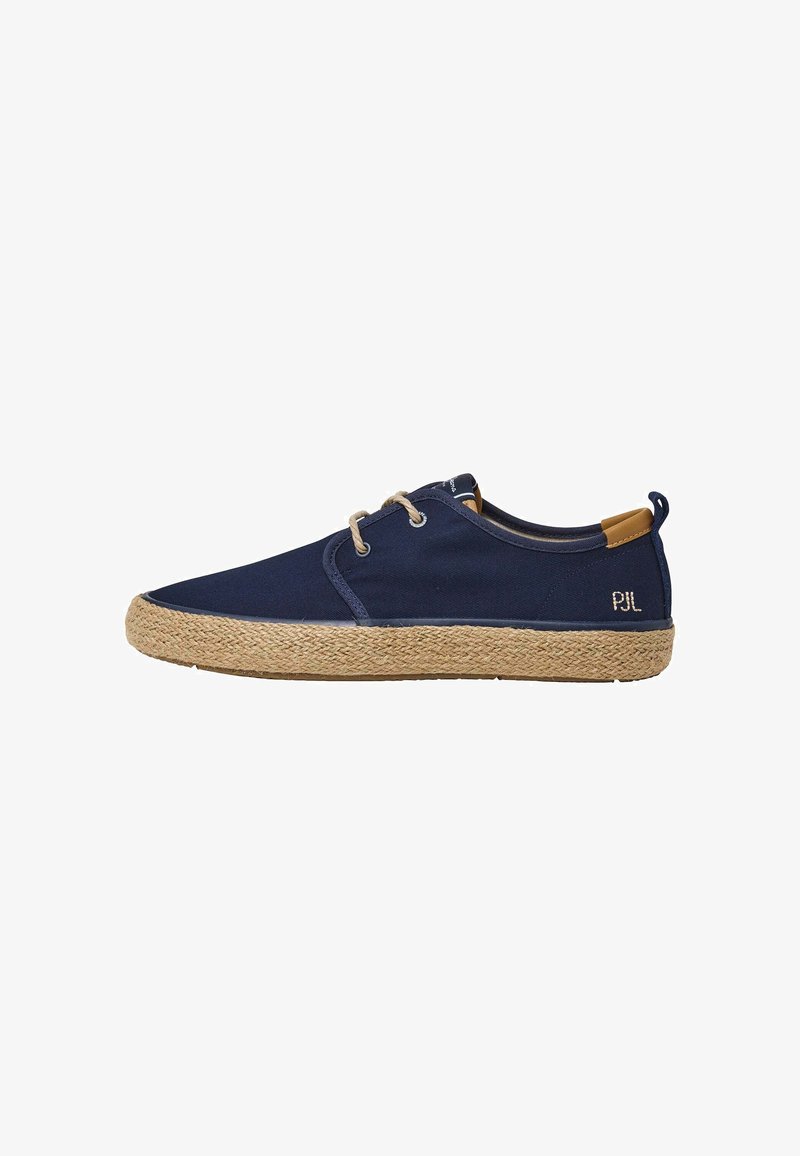 Tumed canvaskinga sneakerid heegeldatud jute tallaga. Omavad metallist aukusid ja kontrastset tan värvi aktsenti kanna juures. Küljel on õmmeldud bränding.