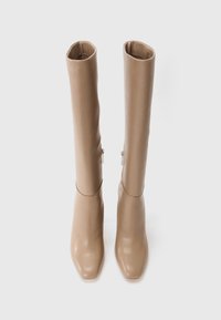 Beige knæhøje støvler lavet af glat læder med firkantet tådesign og sidelukkere, der har en tætsiddende silhuet og minimale detaljer.