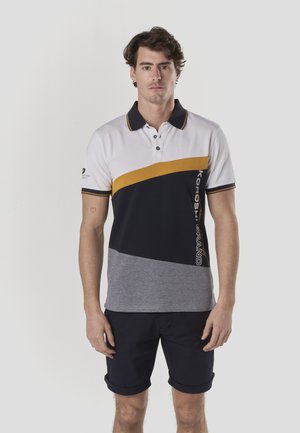 Polo con diseño tricolor: blanco, azul marino y gris, con una franja amarilla y detalles de logo. Manga corta, con cuello, mezcla de algodón.