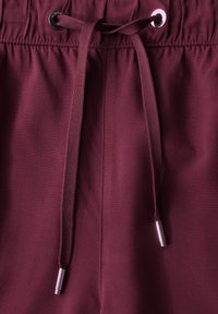 Bordeaux casual broeken met een elastiche tailleband en een trekkoord. Voorzien van metalen aglets en een gladde stofstructuur.
