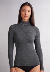 Grijze geribbelde coltrui met lange mouwen, getailleerd ontwerp, gemaakt van textiel met structuur, met een hoge halslijn en smalle mouwen.