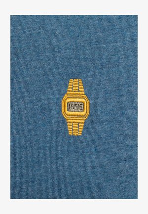 Blauwe stof heeft een geborduurd ontwerp van een gele polshorloge met een rechthoekige wijzerplaat en een armband van drie schakels, waarop "1995" staat.